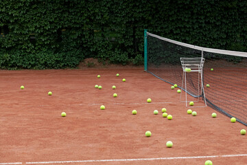 Tennis balls scattered on clay tennis court. Outdoor sports ground. Training. Selective focus, copy space. Design element