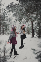 Fototapeta na wymiar Close up fashion portrait of two sisters hugs and having fun winter time,wearing pink hats, rabbit ears and sweater,best friends couple outdoors, snowy weather