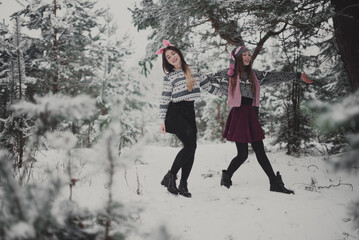 Fototapeta na wymiar Close up fashion portrait of two sisters hugs and having fun winter time,wearing pink hats, rabbit ears and sweater,best friends couple outdoors, snowy weather