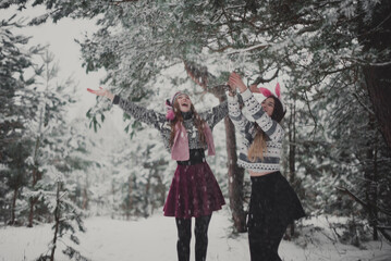 Close up fashion portrait of two sisters hugs and having fun winter time,wearing pink hats, rabbit ears and sweater,best friends couple outdoors, snowy weather