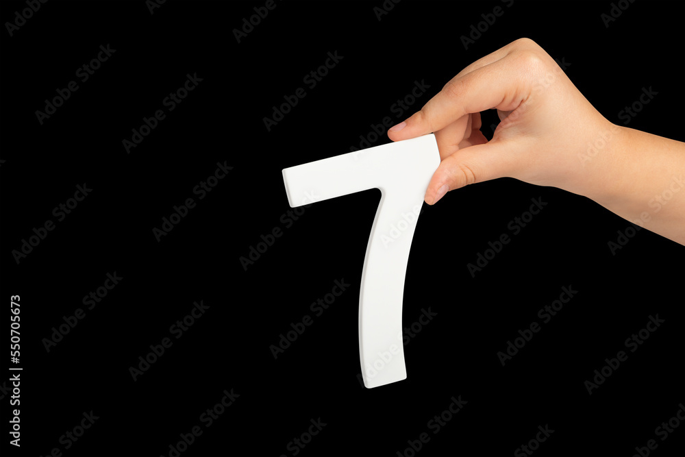 Poster number seven in hand isolated on black background. number 7 in a child's hand on a black background.