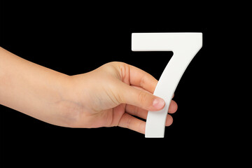Number seven in hand isolated on black background. Number 7 in a child's hand on a black...