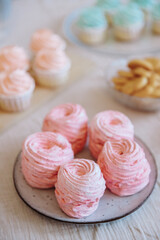 A table with lots of cupcake cakes, marshmallows in pink and blue shades, shortbread cookies. Table setting for gender party parties