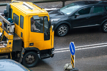 A tow truck on the road with a broken car on a trailer. An accident on the road in the city. Evacuation of a broken car after an accident.