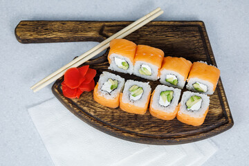 Japanese Philadelphia rolls on a wooden cutting board on a table in the kitchen