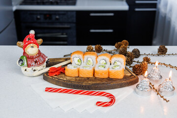 Japanese Philadelphia rolls on a wooden cutting board on a table in the kitchen. Christmas decoration. New Year concept
