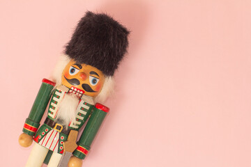 Interesting beautiful christmas nutcracker soldier on pink colored paper surface texture with copy...