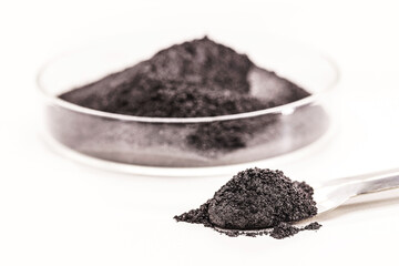 black pigment, powder for industrial or cosmetic use, isolated white background, in petri dish