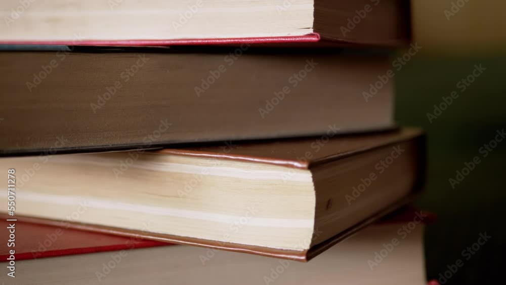 Poster close-up of a stack of colorful old hardcover books in rays of sunlight. camera movement from the bo