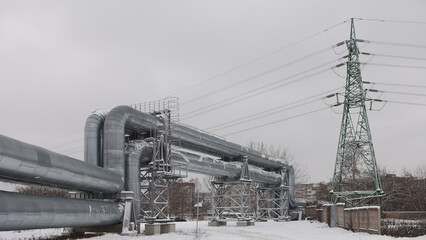 pipeline and power line in the city in winter against the gray sky