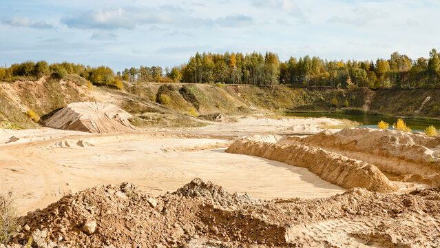 a sand quarry, in the photo a quarry against a background of blue sky and clouds also in the background trees shrubs and forest