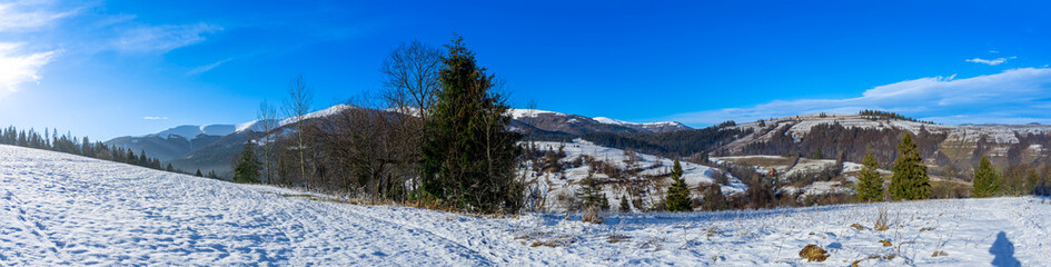 Sun over snowy Nord-East slopes of Polonina Borzhava from Izky village, Carpathian mountains, Ukraine