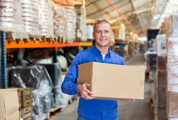 Portrait of loader with a large box in his hands in a store warehouse