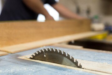 Young carpenter cutting wooden boards for furniture in his workshop