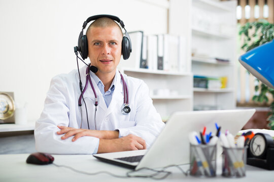 Doctor In Headphones Consults Patient Using Laptop And The Internet. Telemedicine, Virtual Visit To Hospital Concept