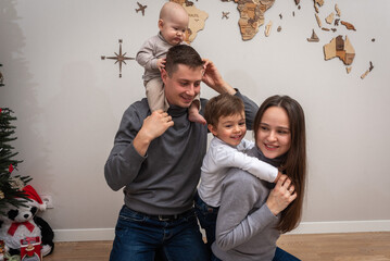 portrait of a young family, father, mother and two small sons, cheerful, friendly and strong family. They smile and hug children in their arms. The concept of a young friendly family	