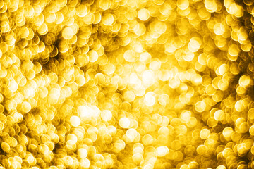 Christmas background. Golden shiny background. Abstract vibrant color glowing white spots texture for graphic design. Bright yellow defocused glitter texture.