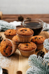 
muffins with chocolate on a wooden stand, powdered sugar, cones, Christmas tree branches nearby