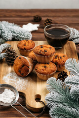 Obraz na płótnie Canvas muffins with chocolate on a wooden stand, powdered sugar, cones, Christmas tree branches nearby