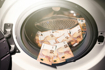 50 euro banknotes inside washing machine. Money laundering symbol. Tax evasion. Illegal financial transactions. Euro currency