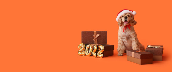Adorable dog in Santa hat and with Christmas gifts on orange background with space for text