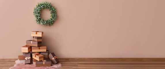 Christmas gifts and beautiful mistletoe wreath hanging on brown wall in room