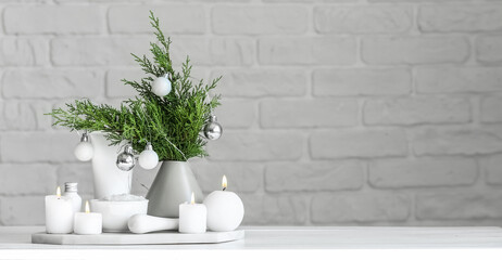Christmas decor with natural cosmetics and aroma candles on table against brick wall