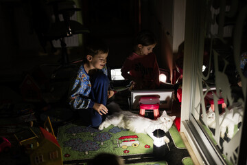 Kids playing with cat at home during a blackout using alternative lighting.