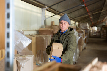 Caucasian man storekeeper using his phone to take photograph of pasteboard box.