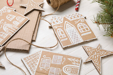 Christmas cardboard stars and houses on white wooden background, closeup