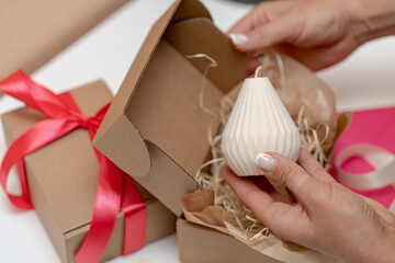 Women's hands are packing a handmade wax candle as gifts for the holiday.