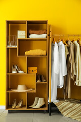 Interior of stylish dressing room with rack, clothes and shelving unit