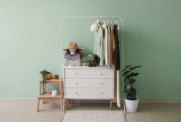 Interior of stylish room with rack, chest of drawers and sweaters