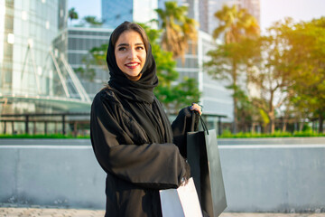 Happy young muslim woman enjoying shopping time in the city of Abu Dhabi. Beautiful Arabic woman...