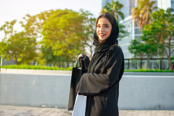 Young muslim woman enjoying shopping time in the city of Abu Dhabi. Beautiful Arabic woman with shopping bags on the street.