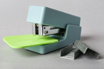 Office stapler with sticky notes and staples on grey background