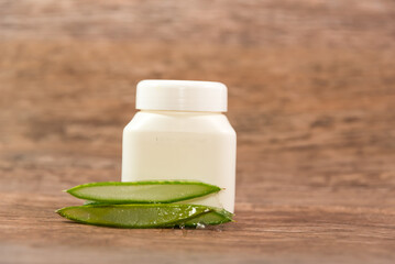 Aloe Vera leaf in pieces next to a plastic container on a wooden table