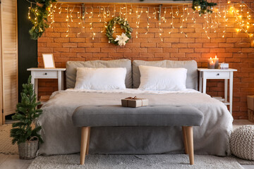 Interior of bedroom with Christmas wreath and glowing lights