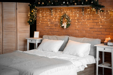 Interior of bedroom with Christmas wreath and glowing lights