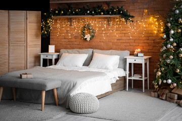 Interior of bedroom with Christmas branches, fir tree and glowing lights