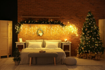 Interior of dark bedroom with Christmas trees, fir branches and glowing lights