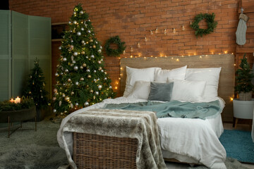 Interior of bedroom with Christmas wreath, fir trees and glowing lights