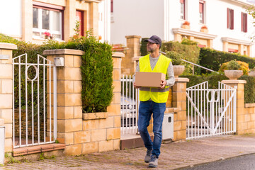 Package delivery driver from an online store, with a box in hand looking for the house