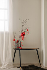 Vase with tree branches, Christmas balls and reed diffuser on table in living room