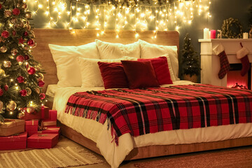 Interior of bedroom with Christmas tree, fireplace and glowing lights at night