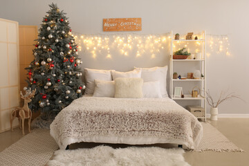 Interior of bedroom with Christmas tree, glowing lights and shelving unit