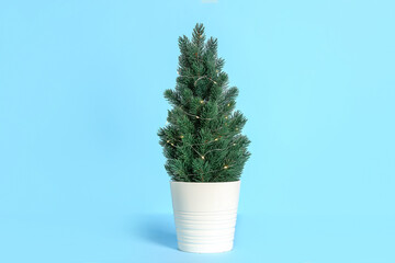 Small Christmas tree with glowing lights on blue background