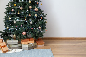 Glowing Christmas tree with presents near light wall