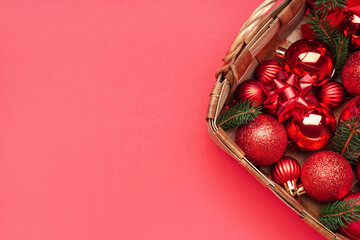 Basket with Christmas balls and fir branches on red background