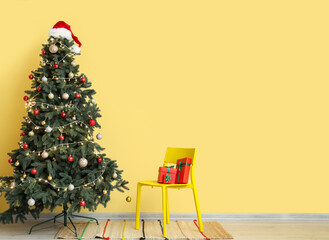 Chair with presents and Christmas tree near yellow wall